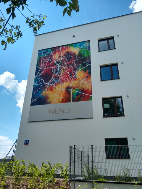 Mural dla dewelopera. Mural jest wykonany w stylu mapy artystycznej Wilna na budynku nowej inwestycji w Warszawie. Dzięki zastosowaniu abstrakcyjnych kolorów oraz minimalistycznej formy mapy, mural wyróżnia się na tle tradycyjnych malowideł ściennych. Jego nowoczesny styl i elegancka kompozycja czynią go uniwersalnym dziełem sztuki, które przemawia do szerokiej publiczności.